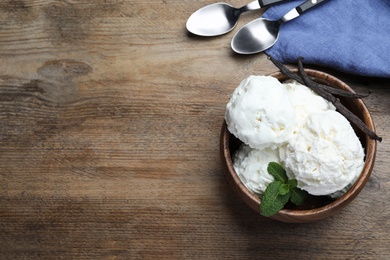 Photo of Yummy vanilla ice cream served on wooden table, flat lay. Space for text