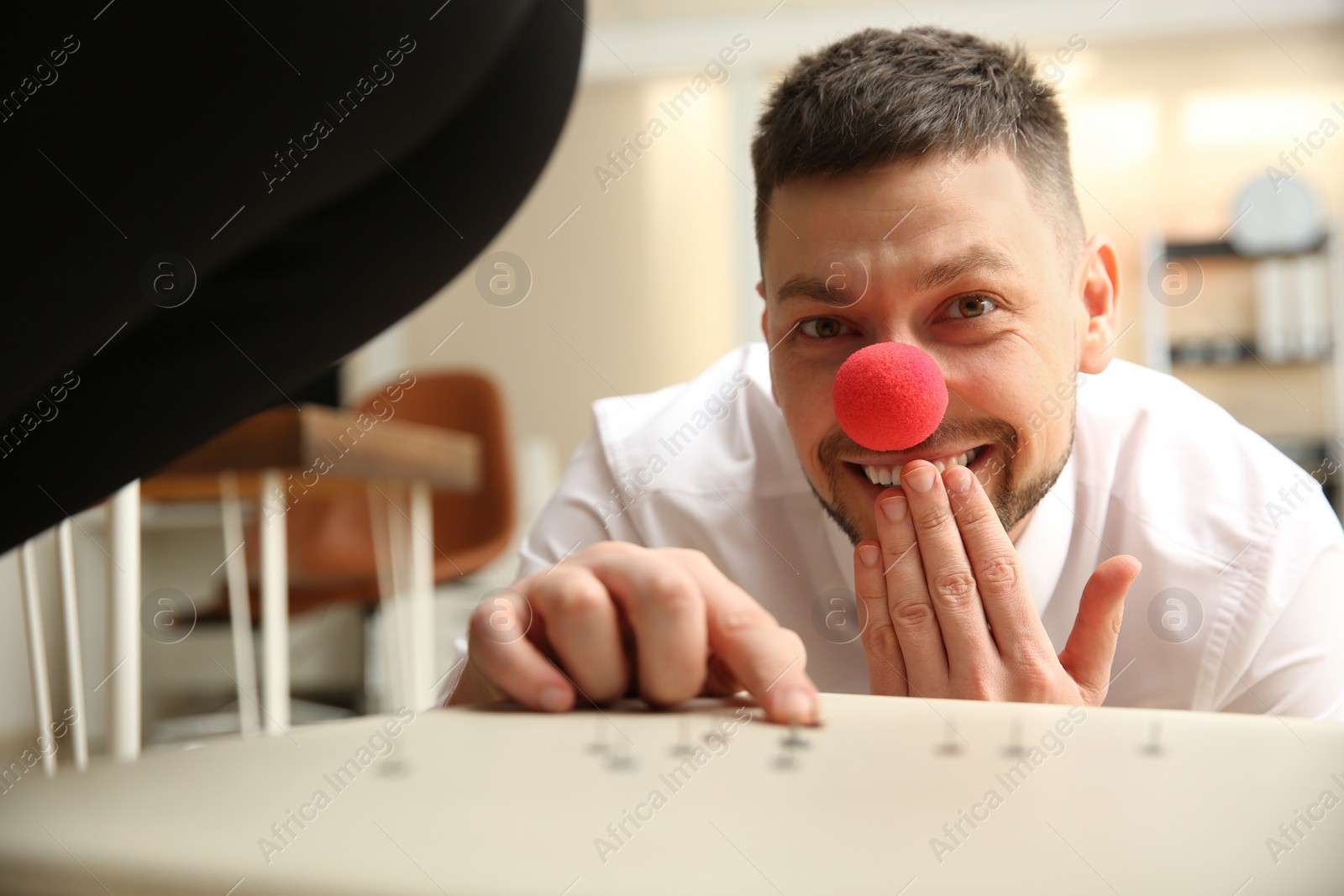 Photo of Man putting pins on chair while his colleague sitting down in office, closeup. Funny joke