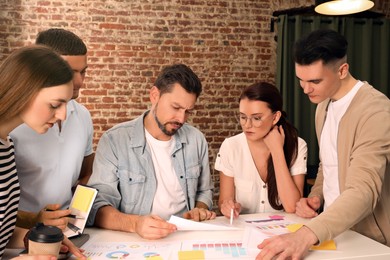 Photo of Team of employees working together in office