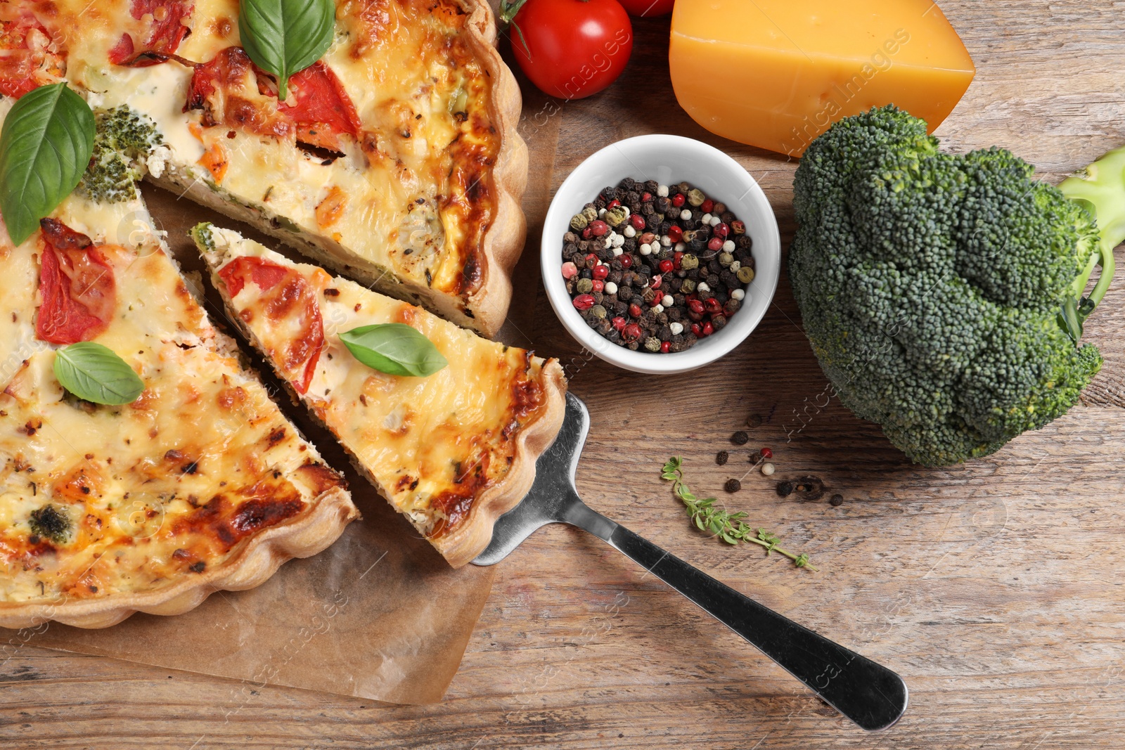 Photo of Taking piece of tasty quiche with tomatoes, basil and cheese on wooden table, flat lay