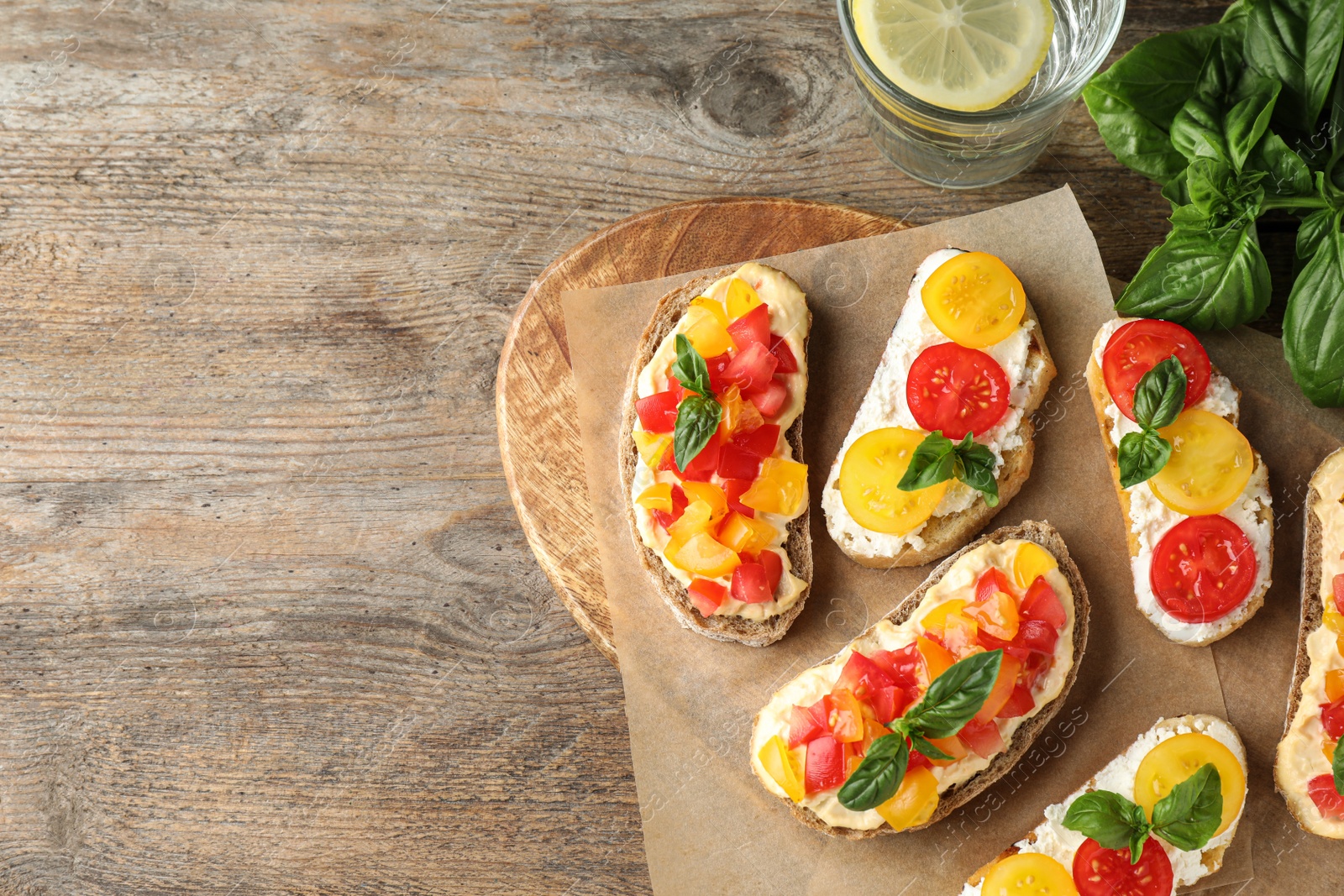 Photo of Tasty fresh tomato bruschettas on wooden table, flat lay. Space for text