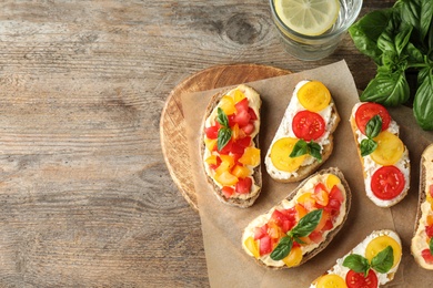 Tasty fresh tomato bruschettas on wooden table, flat lay. Space for text