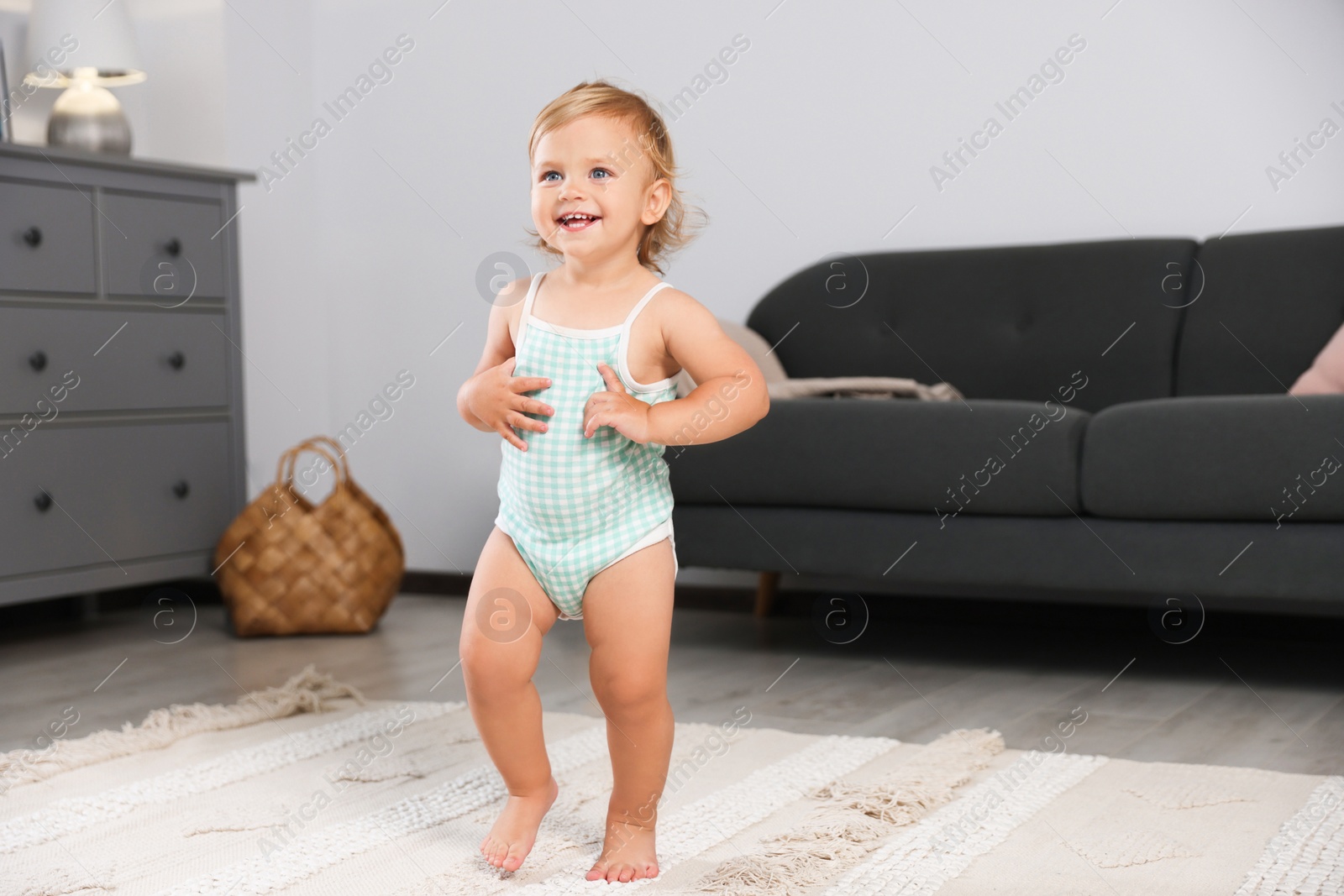 Photo of Cute baby learning to walk in living room