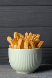 Photo of Bowl of french fries on grey wooden table