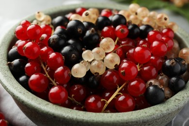 Photo of Different fresh ripe currants in bowl, closeup