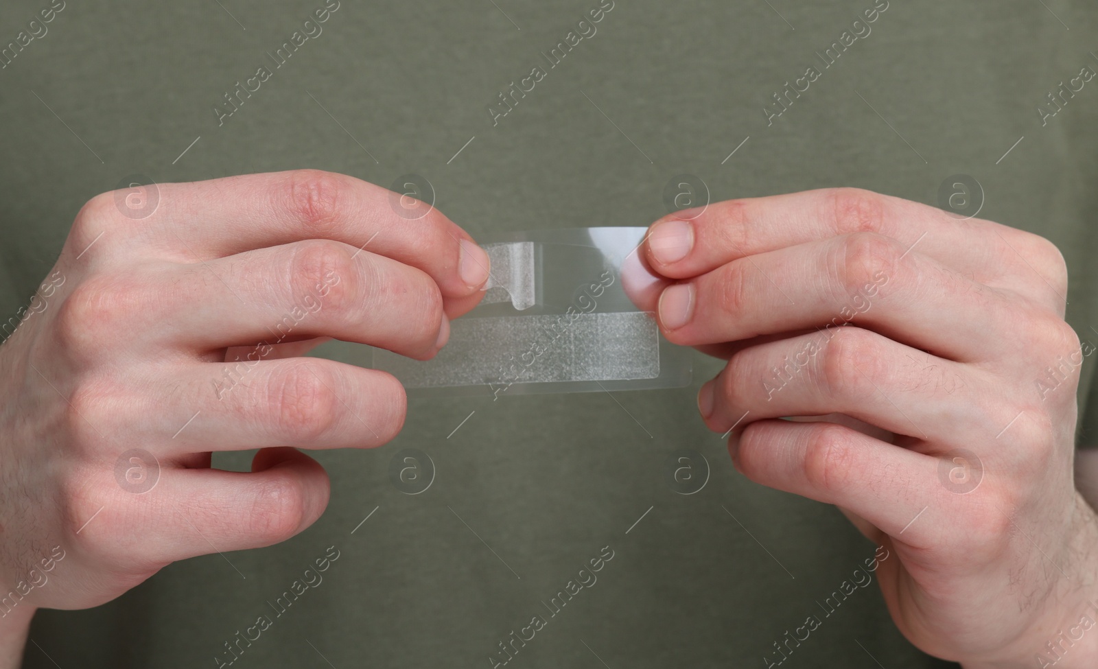 Photo of Young man with whitening strips, closeup of hands