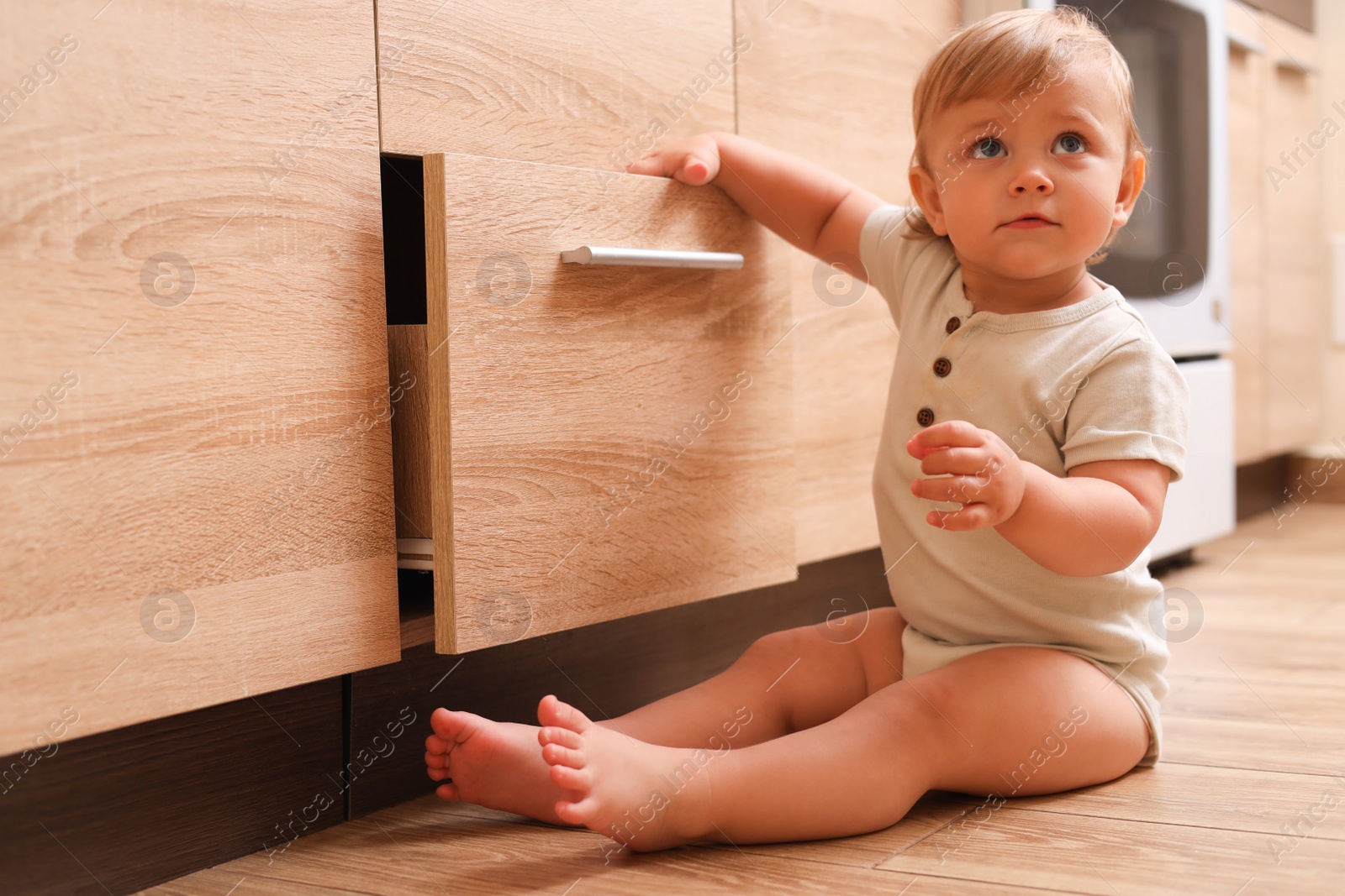 Photo of Little child exploring drawer in kitchen. Dangerous situation