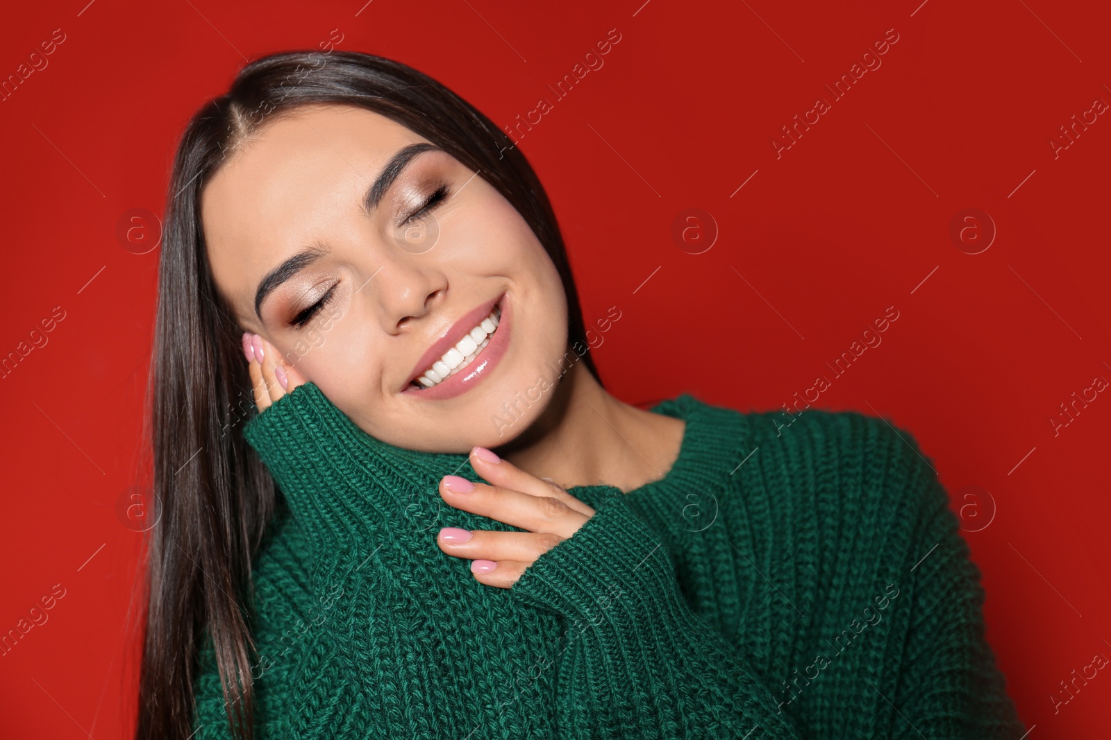 Image of Happy young woman wearing warm sweater on red background 