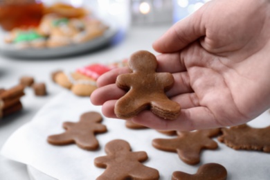 Making homemade Christmas cookies. Woman holding gingerbread man, closeup