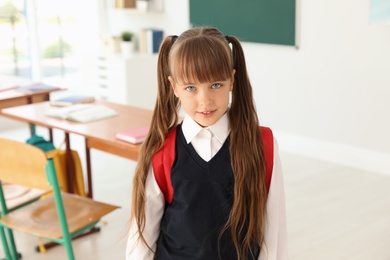 Photo of Little girl in classroom. Stylish school uniform