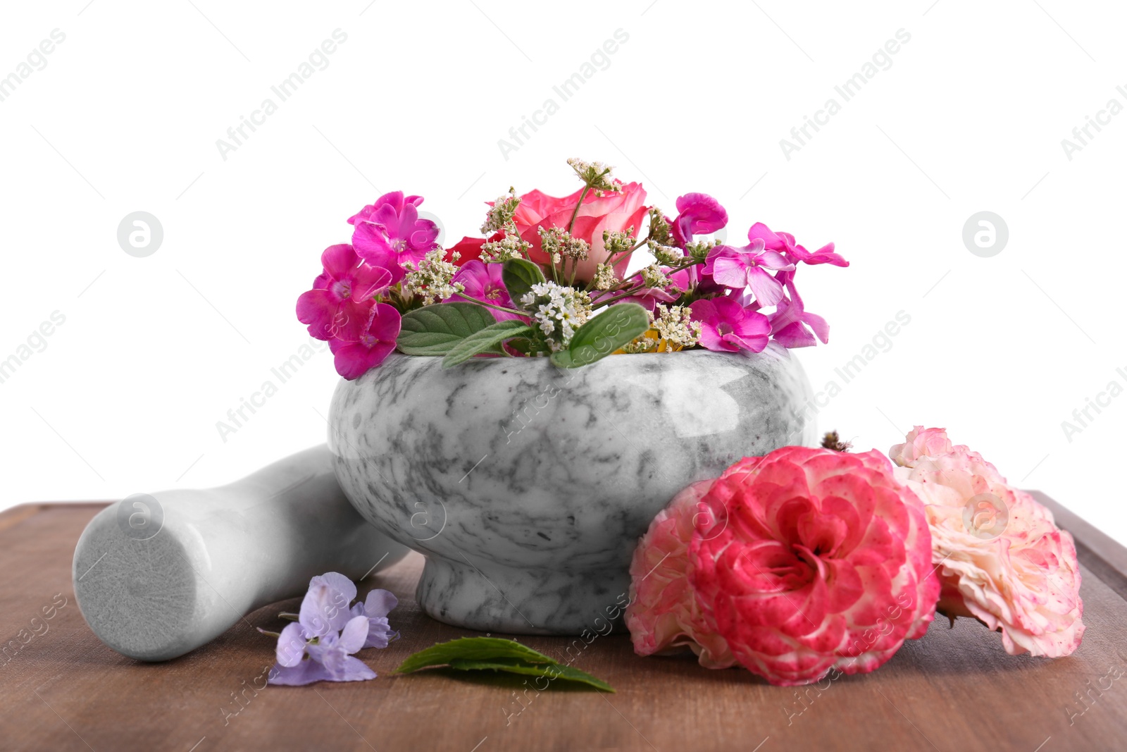 Photo of Marble mortar, pestle and different flowers on wooden board against white background