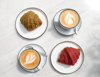 Photo of Delicious croissants and coffee on white marble table, flat lay