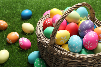 Colorful Easter eggs in basket on green grass