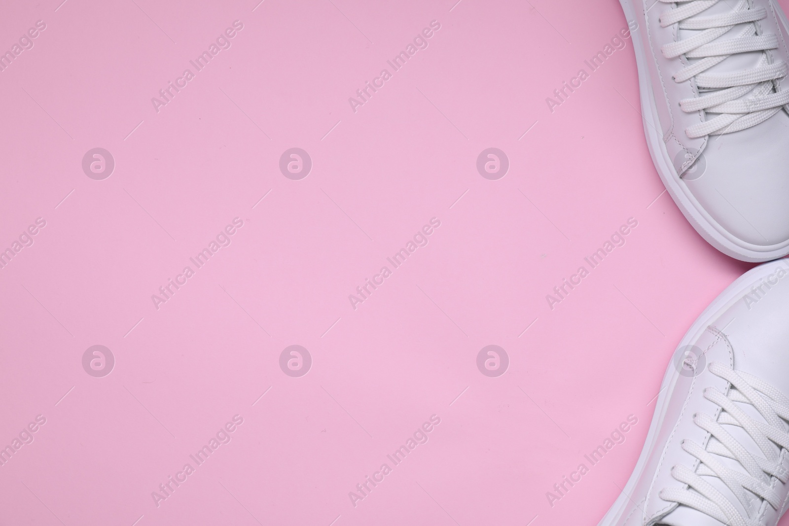 Photo of Pair of stylish white sneakers on pink background, top view. Space for text