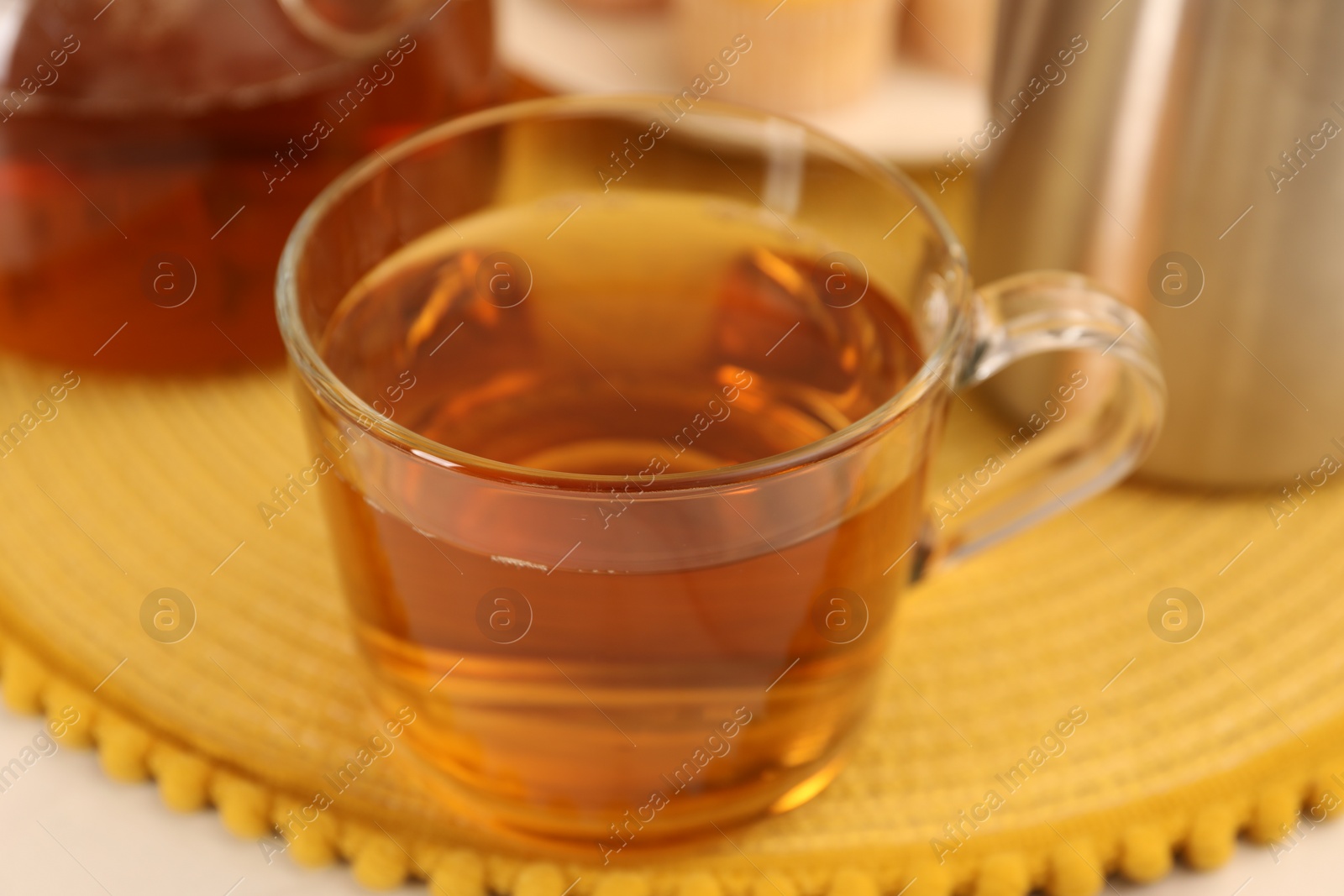 Photo of Aromatic tea in glass cup on table, closeup