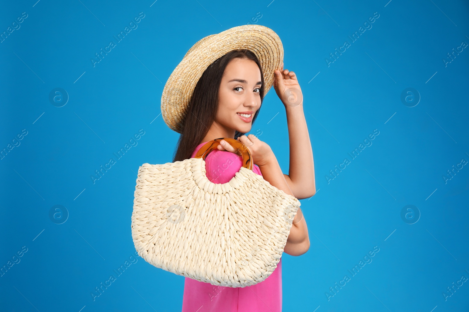 Photo of Young woman with stylish straw bag on light blue background