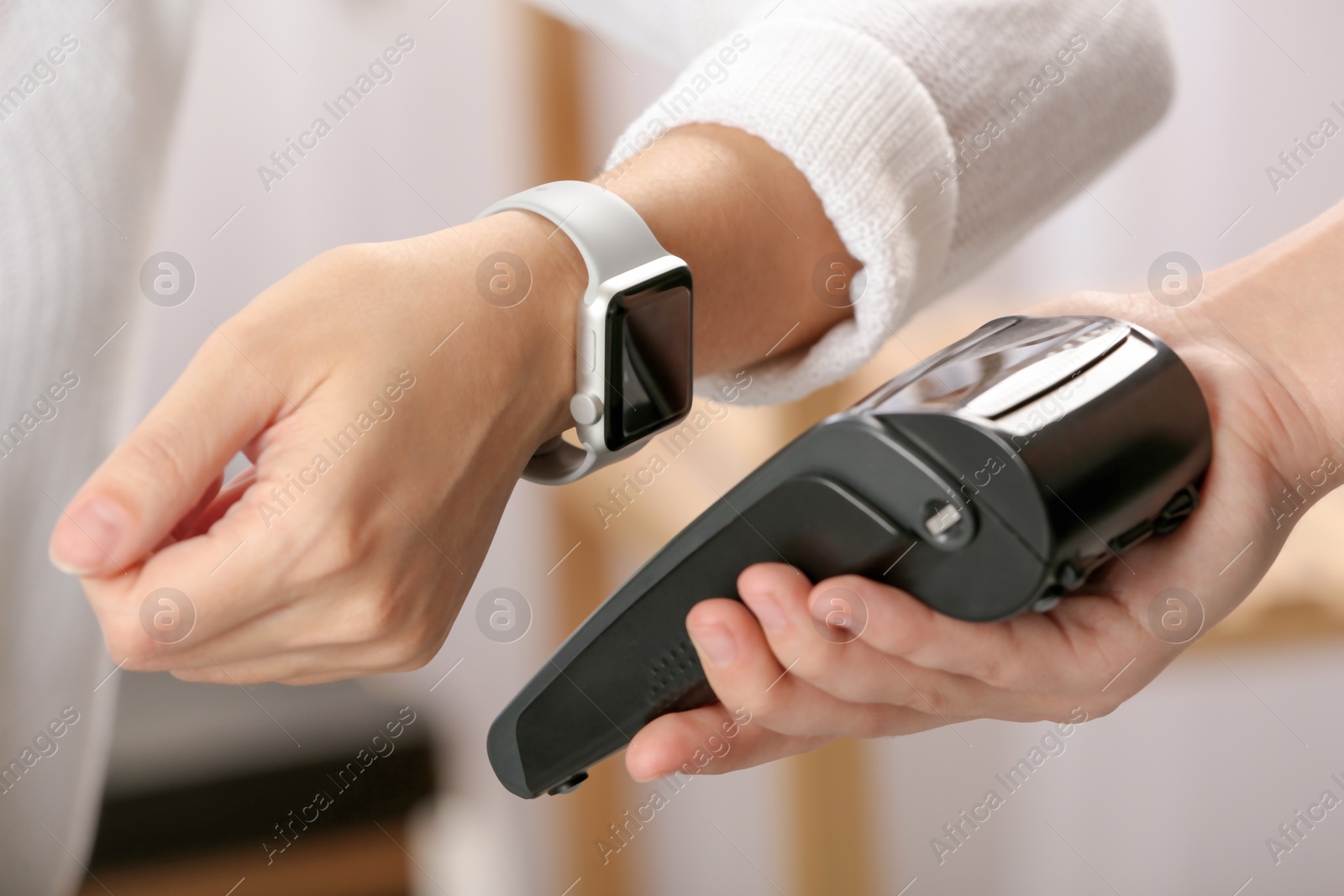 Photo of Woman using terminal for contactless payment with smart watch indoors