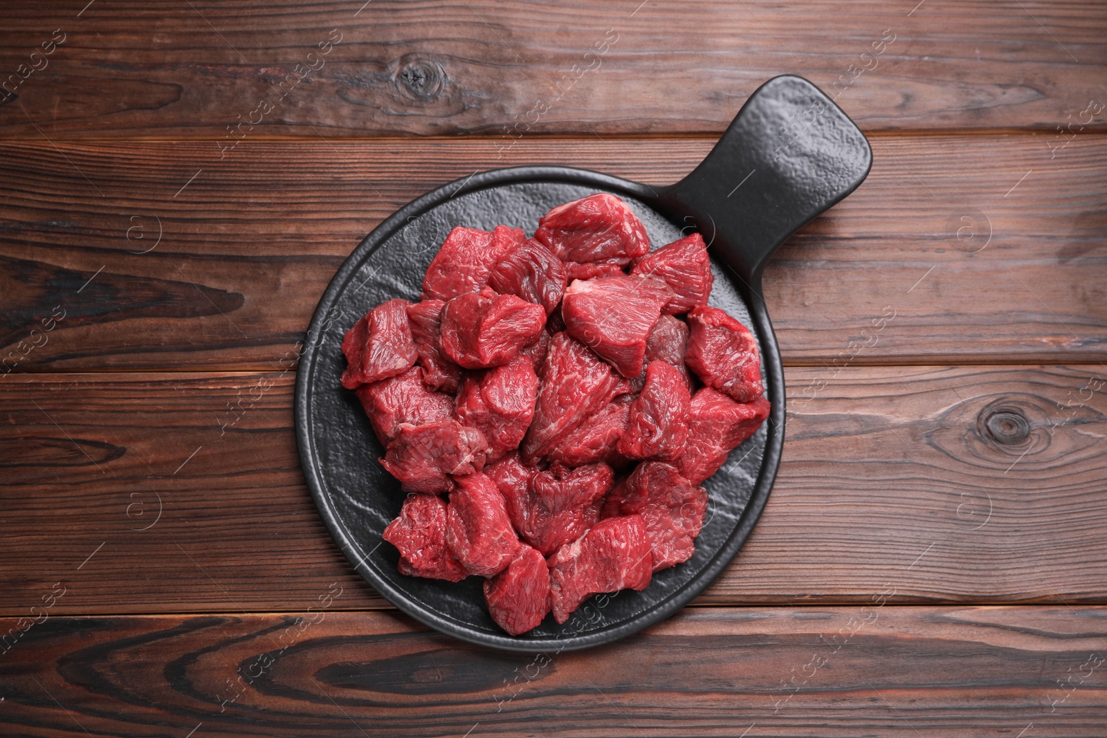 Photo of Pieces of raw beef meat on wooden table, top view