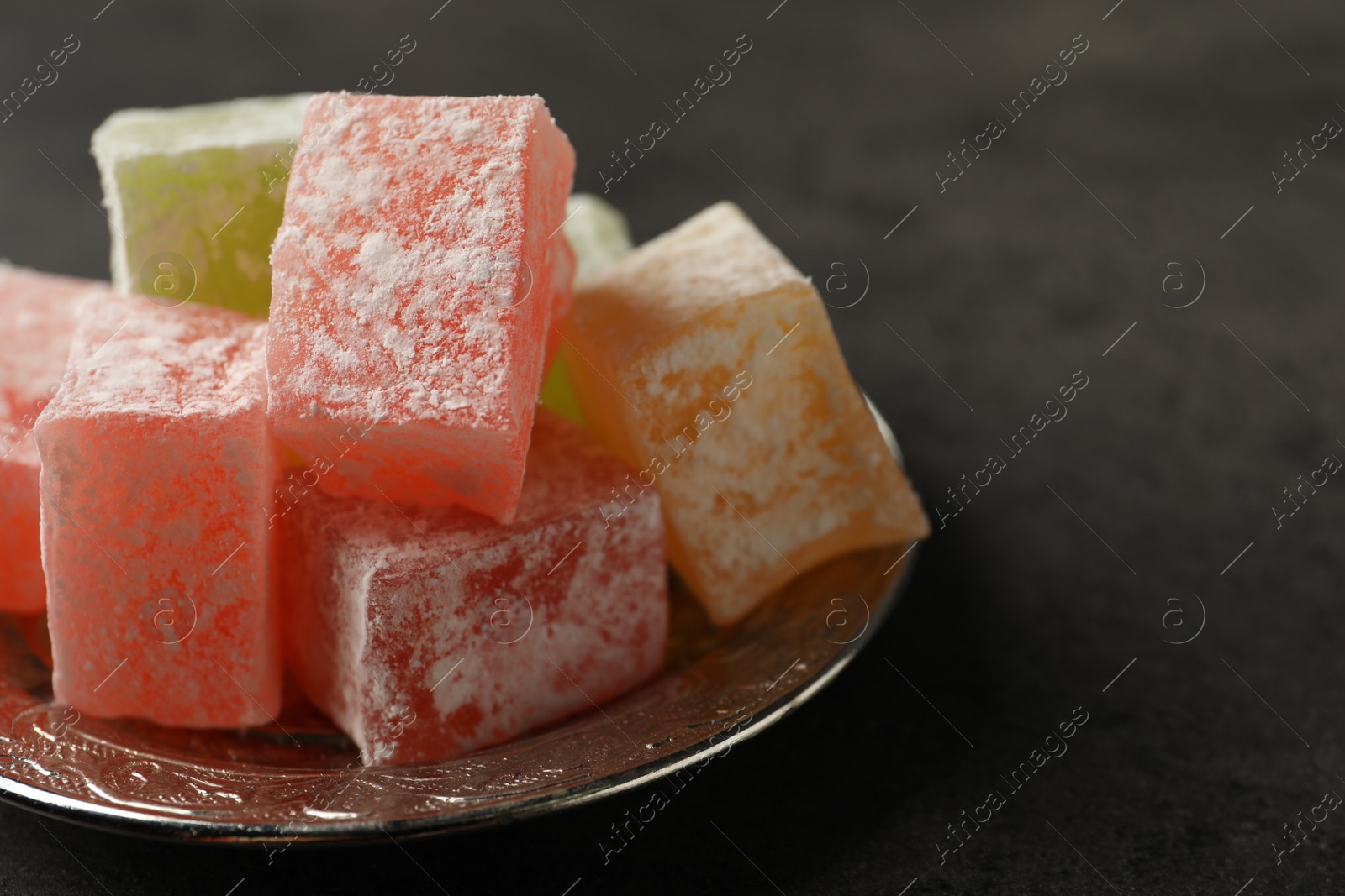 Photo of Turkish delight dessert on dark table, closeup. Space for text