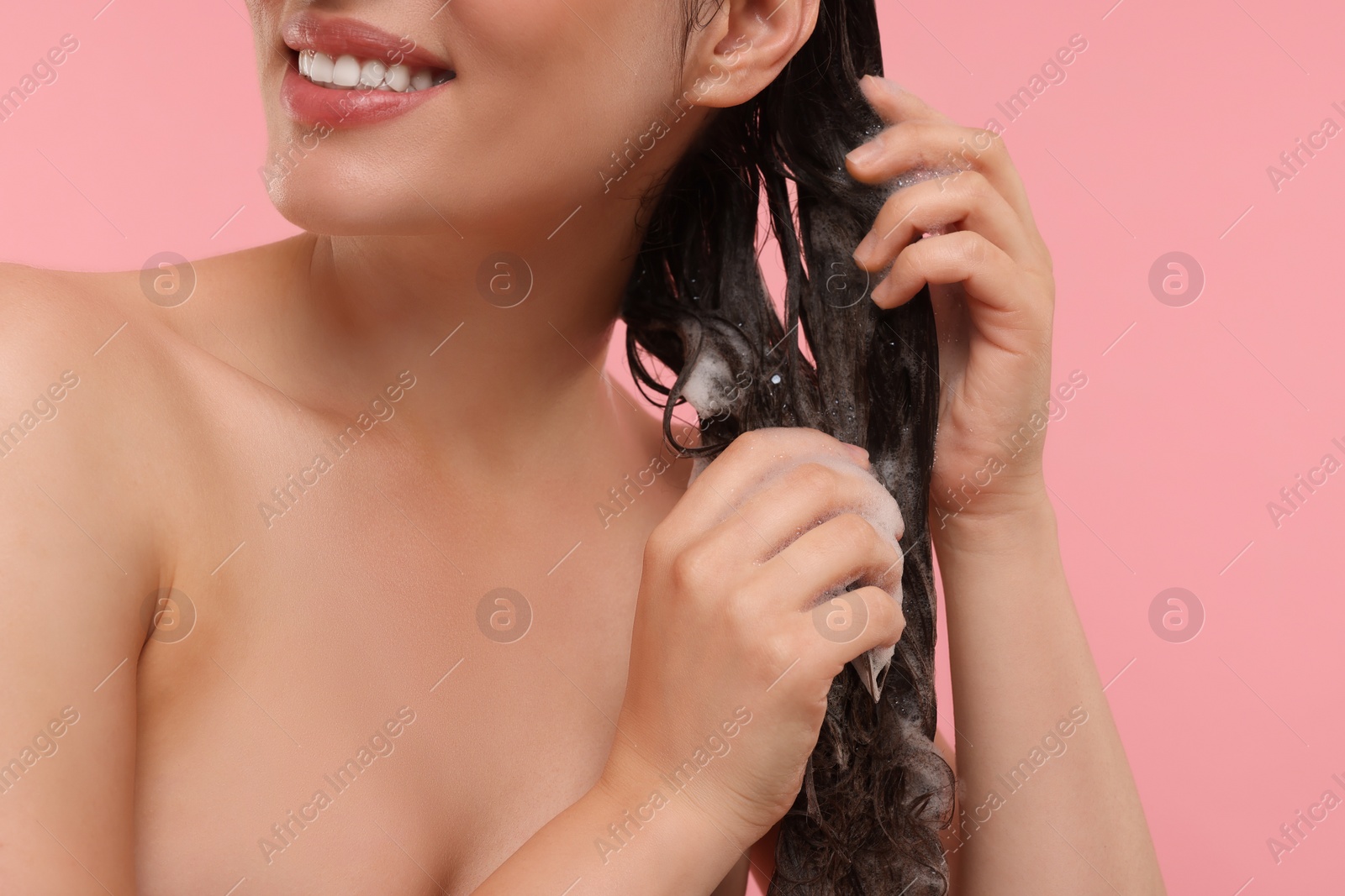 Photo of Happy woman washing hair on pink background, closeup