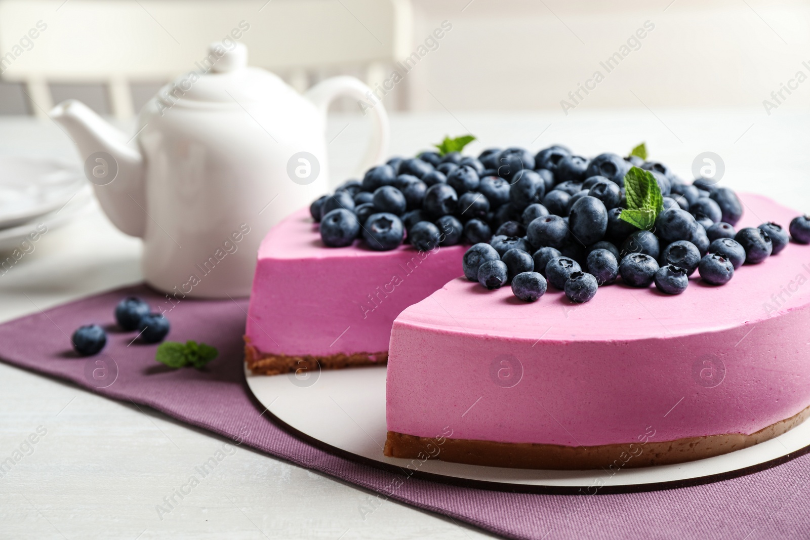 Photo of Tasty cake decorated with blueberries and mint on light table. Space for text