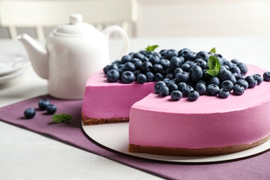 Photo of Tasty cake decorated with blueberries and mint on light table. Space for text