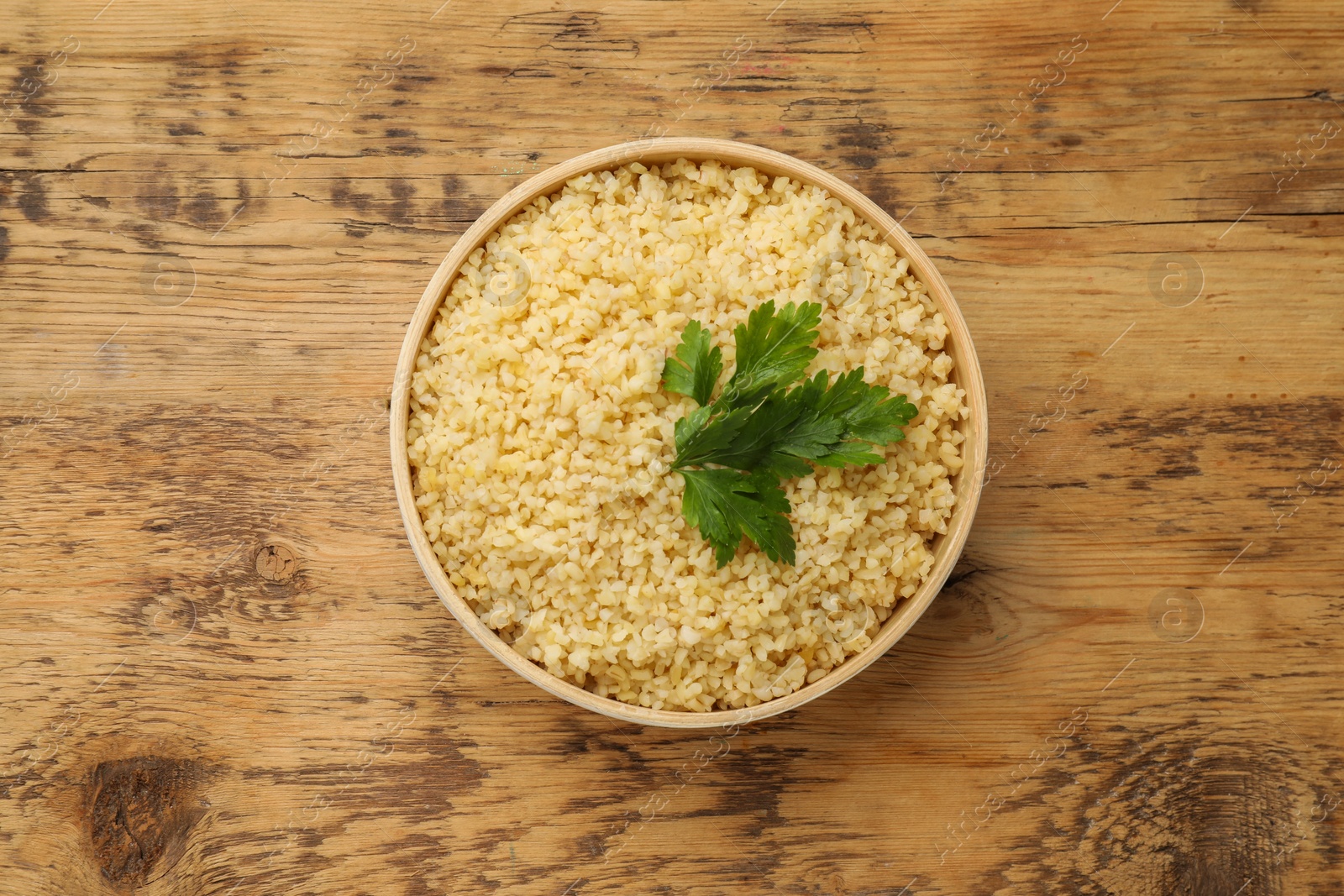 Photo of Delicious bulgur with parsley on wooden table, top view