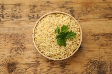 Delicious bulgur with parsley on wooden table, top view