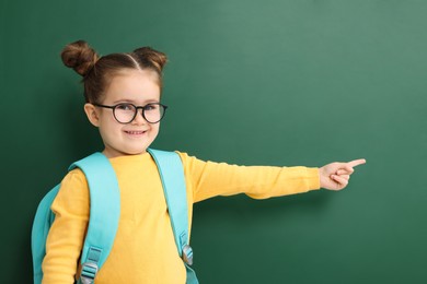 Photo of Happy little school child with backpack pointing at chalkboard