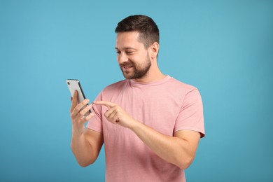 Photo of Man sending message via smartphone on light blue background