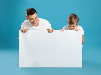Dad and his son with empty banner on color background. Space for design