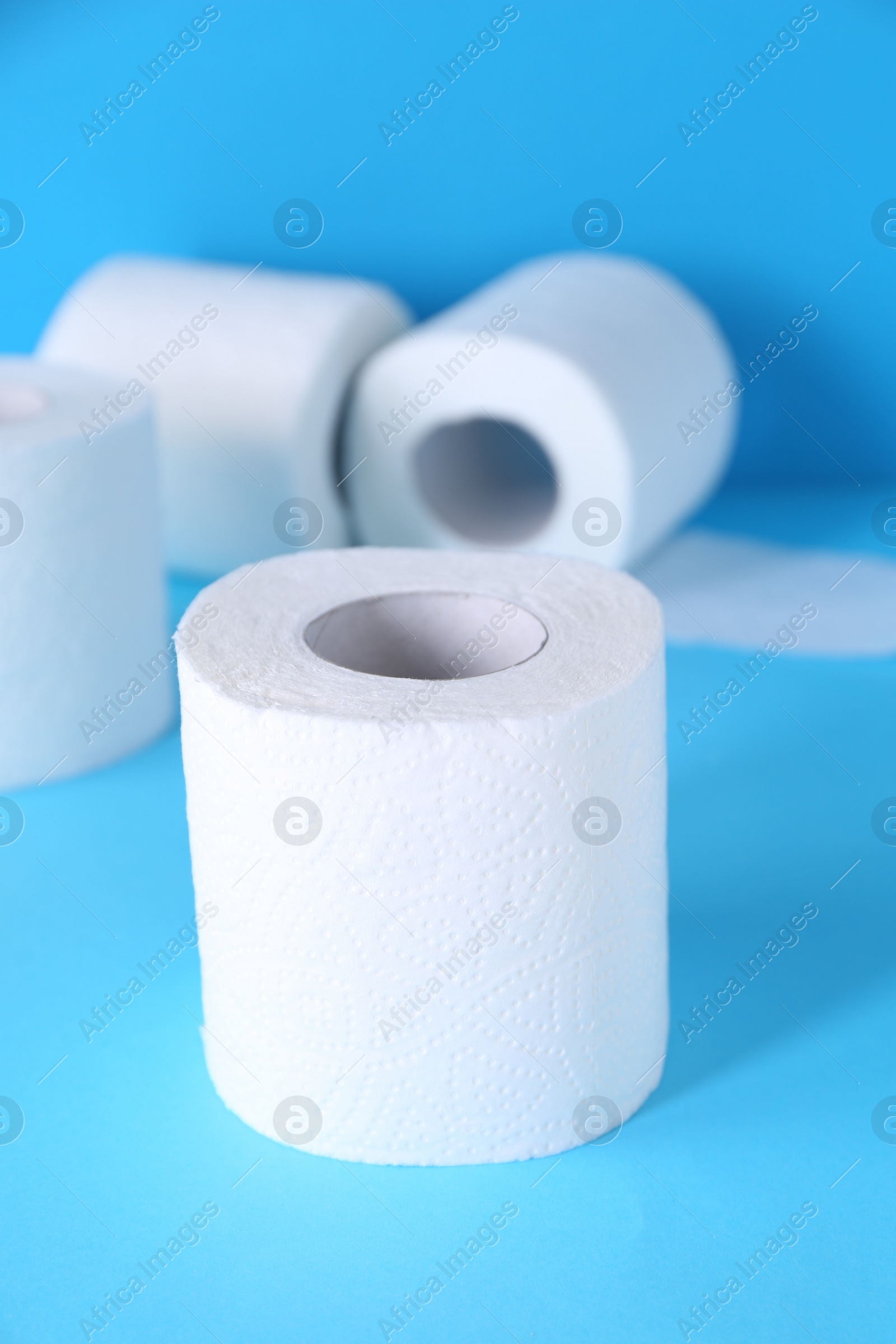 Photo of Soft toilet paper rolls on light blue background