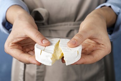 Photo of Woman breaking delicious brie cheese on color background, closeup