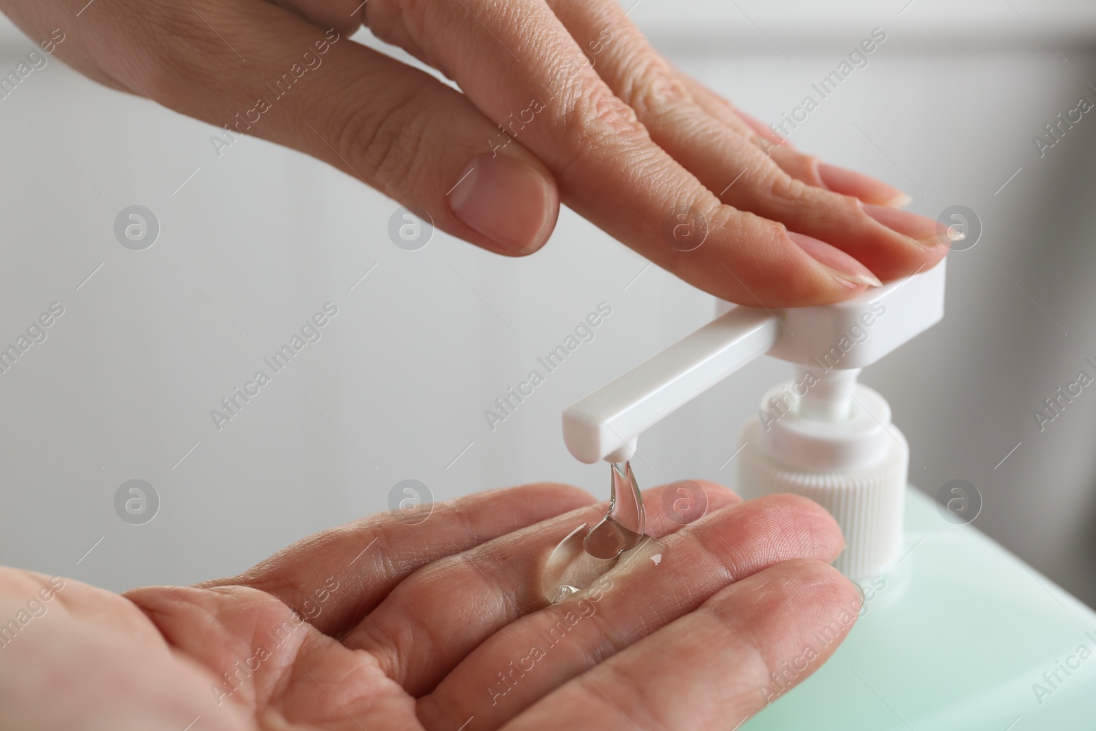 Photo of Woman applying antiseptic gel on hand indoors, closeup