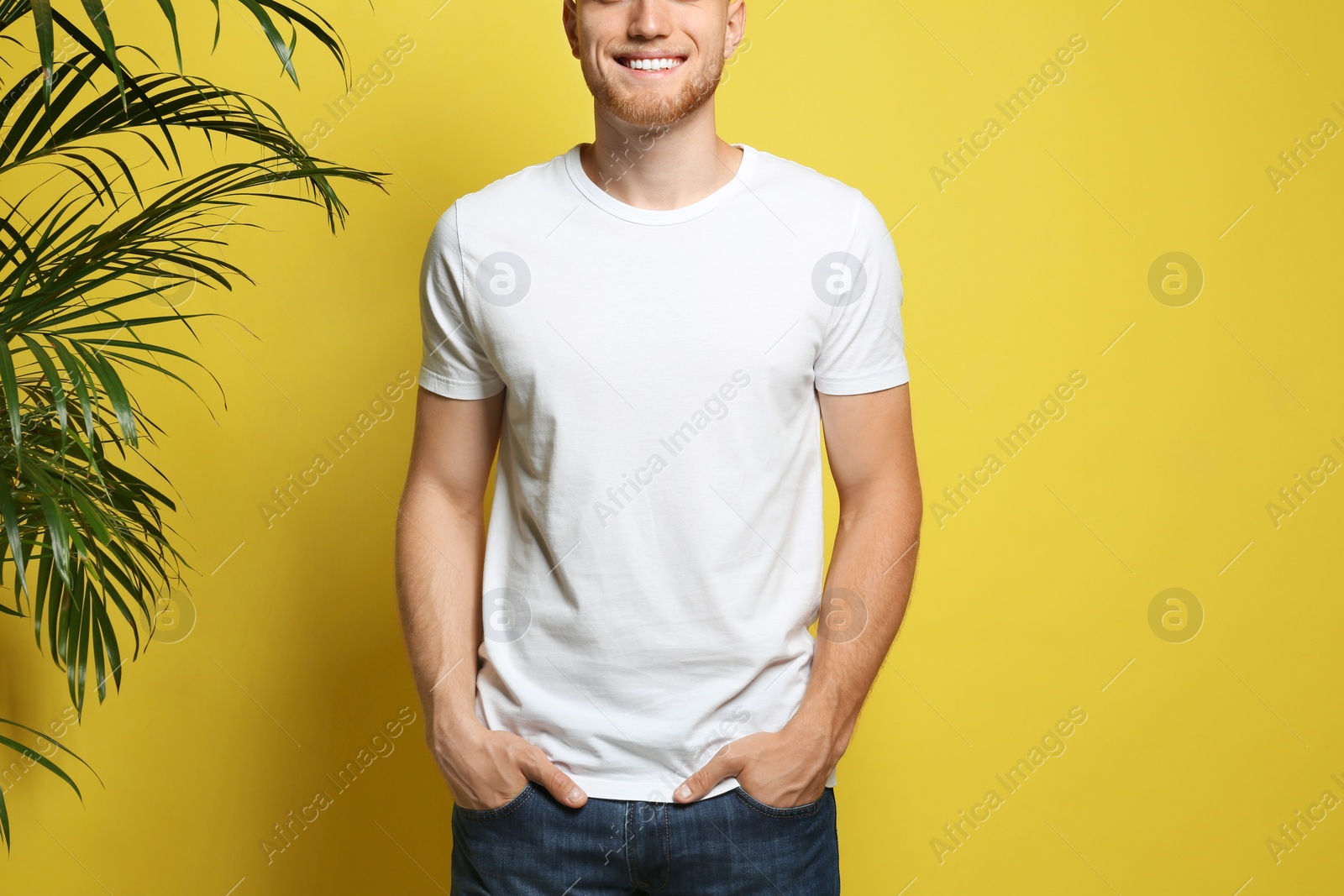 Photo of Young man wearing blank t-shirt on yellow background, closeup. Mockup for design