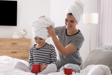 Photo of Young mother and her daughter spending time together on bed at home