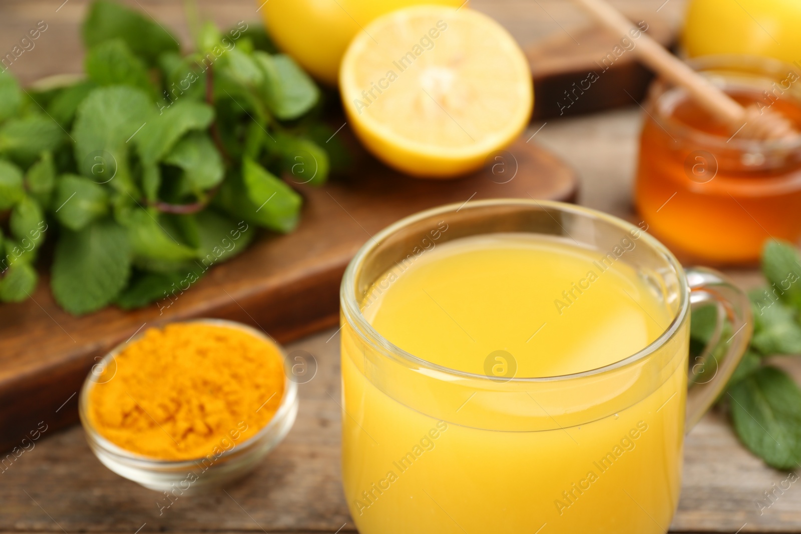 Photo of Immunity boosting drink and ingredients on wooden table, closeup