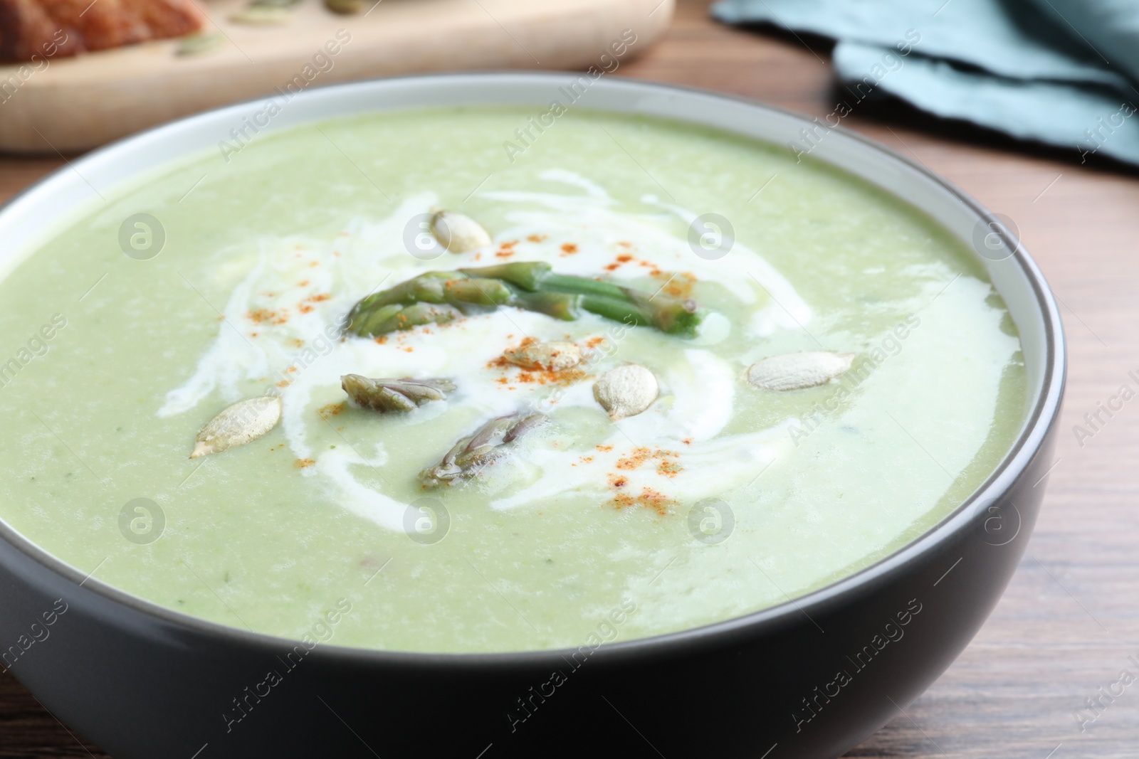 Photo of Delicious asparagus soup with pumpkin seeds on table, closeup