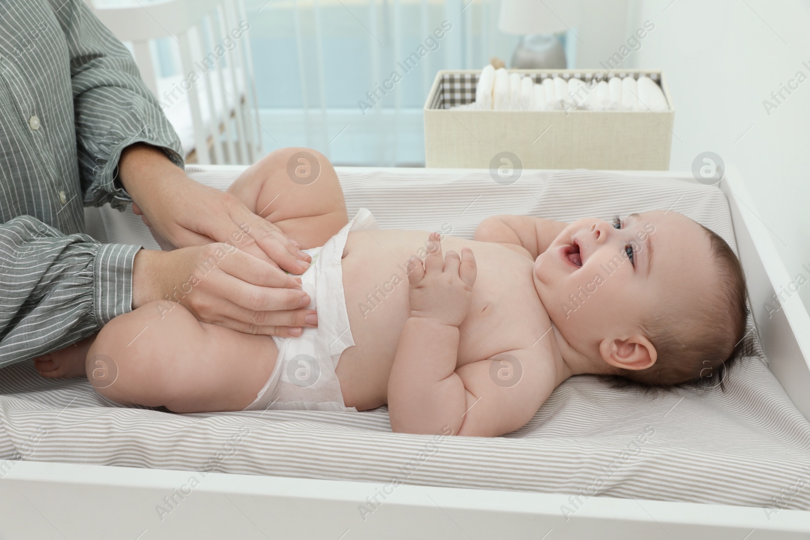 Photo of Mother changing baby's diaper on table at home