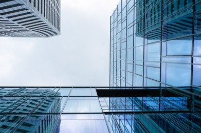 Photo of Stylish buildings with many windows under cloudy sky, low angle view