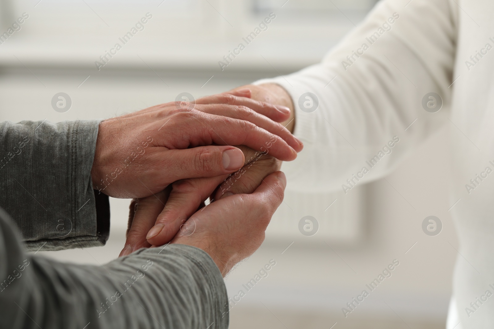 Photo of Trust and support. Men joining hands indoors, closeup