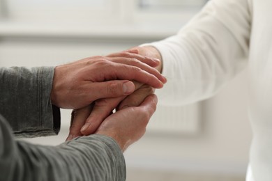 Trust and support. Men joining hands indoors, closeup