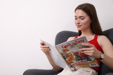 Photo of Young woman reading cooking magazine indoors. Space for text