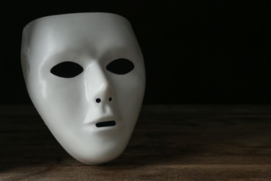 White theatre mask on wooden table, space for text