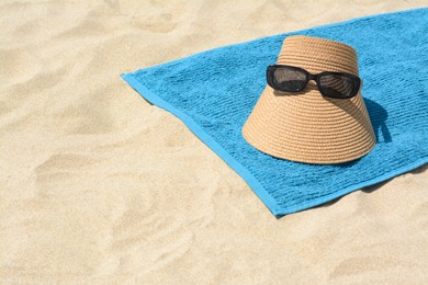 Photo of Towel, straw visor cap and sunglasses on sand, space for text. Beach accessories