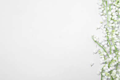 Photo of Beautiful lily of the valley flowers on light grey background, flat lay. Space for text