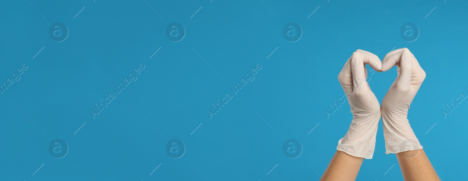 Image of Doctor in medical gloves showing heart with hands on light blue background, closeup. Banner design with space for text 