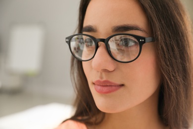 Photo of Beautiful young woman wearing glasses on blurred background. Ophthalmologist service