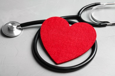 Photo of Stethoscope and red heart on gray background. Cardiology concept
