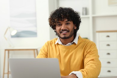 Handsome smiling man using laptop in room